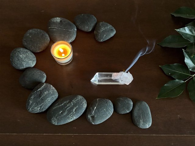 Batu, kristal dan lilin di atas kayu gelap